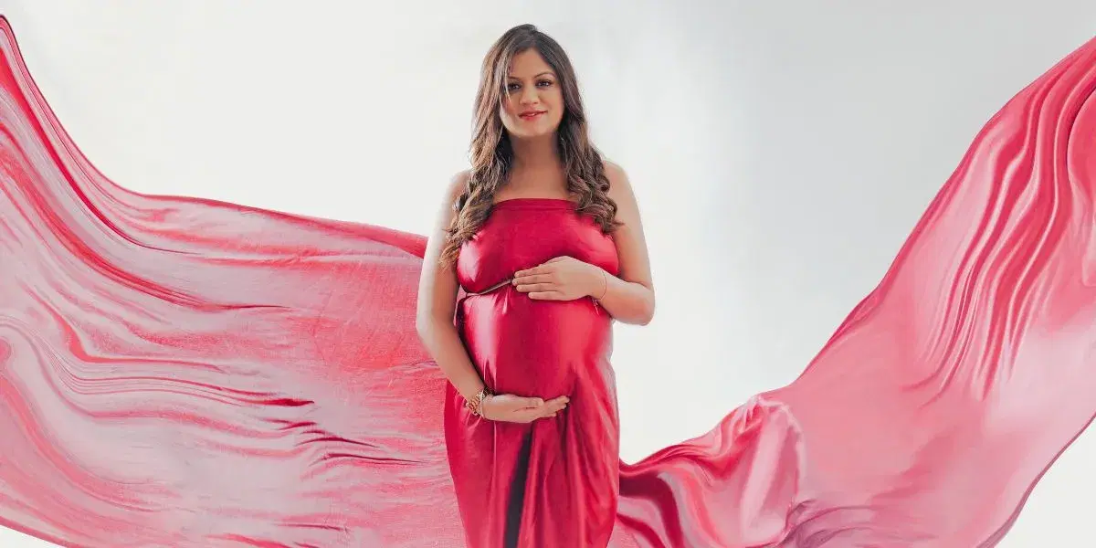 A Pregnant woman in red gown posing for her maternity shoot